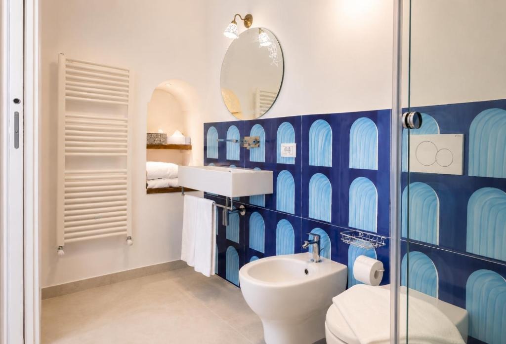 Bathroom with blue arch tiles, round mirror and brass fixtures