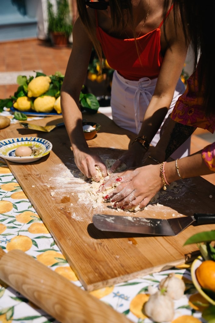Hands kneading fresh pasta dough during a terrace cooking class